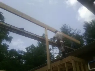 Carpenter setting a ridge beam over a new addition frame — Ice Dam Removal by Roofing Brothers in Jansen