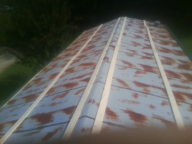 Rusted metal roof panels with new wood purlins before replacement — Storm Damage Roof Repair in Jansen by Roofing Brothers