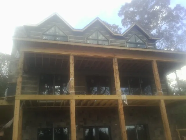 Dormers and porch framing on a large log home under construction — Roof Coating work by our crew in Jansen