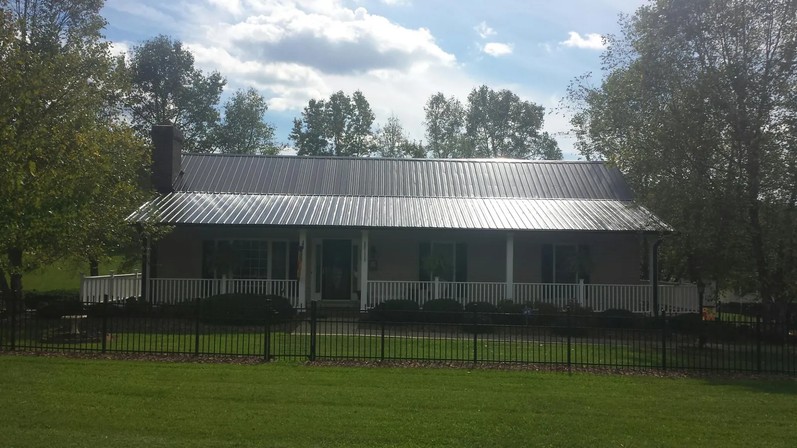 Gray metal roof on a brick ranch with a full width front porch — Gutter Guard Installation work by our crew in Jansen