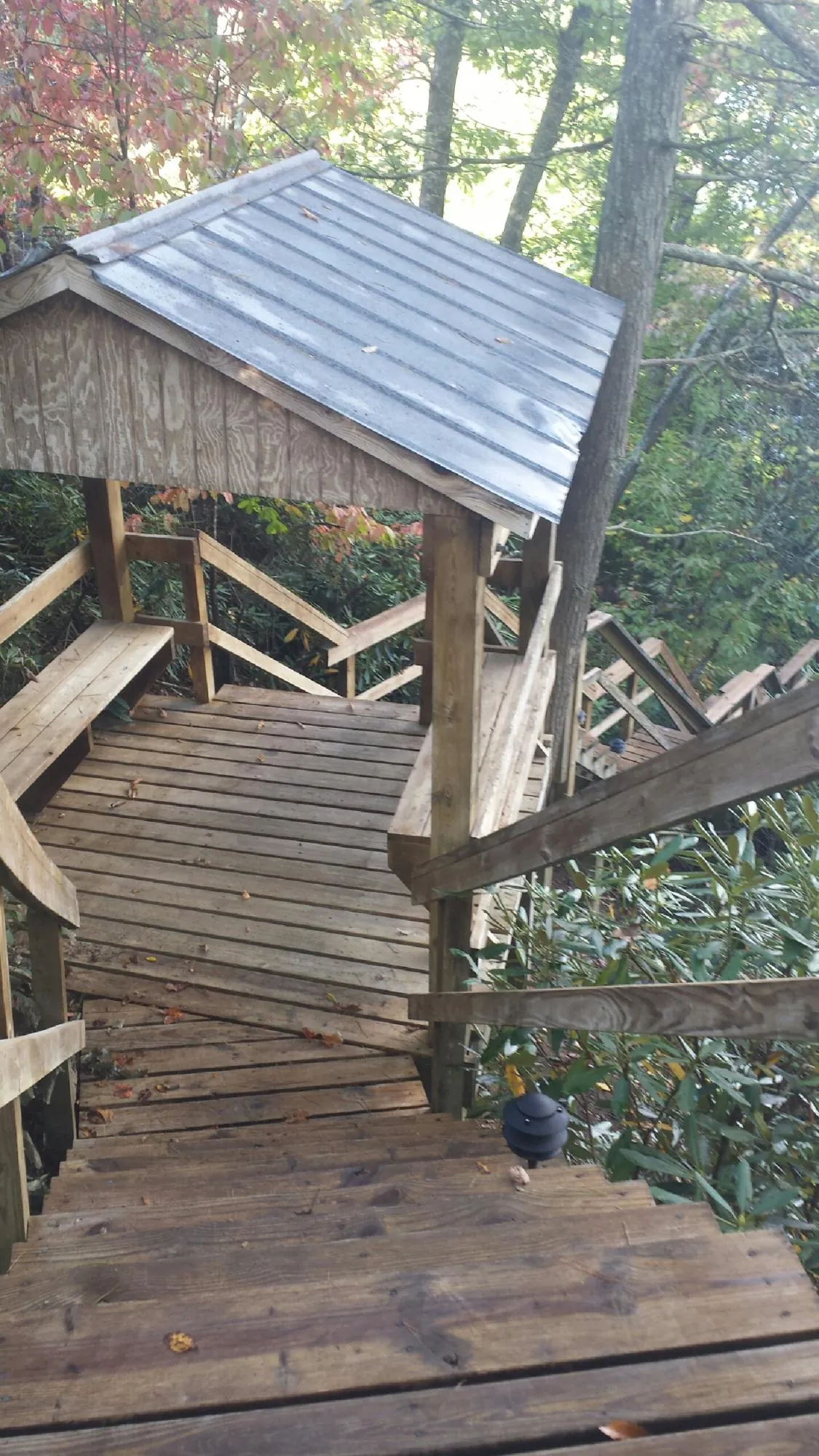 Metal roofed shelter over wooden steps on a wooded walkway — Skylight Repair & Installation work by our crew in Jansen