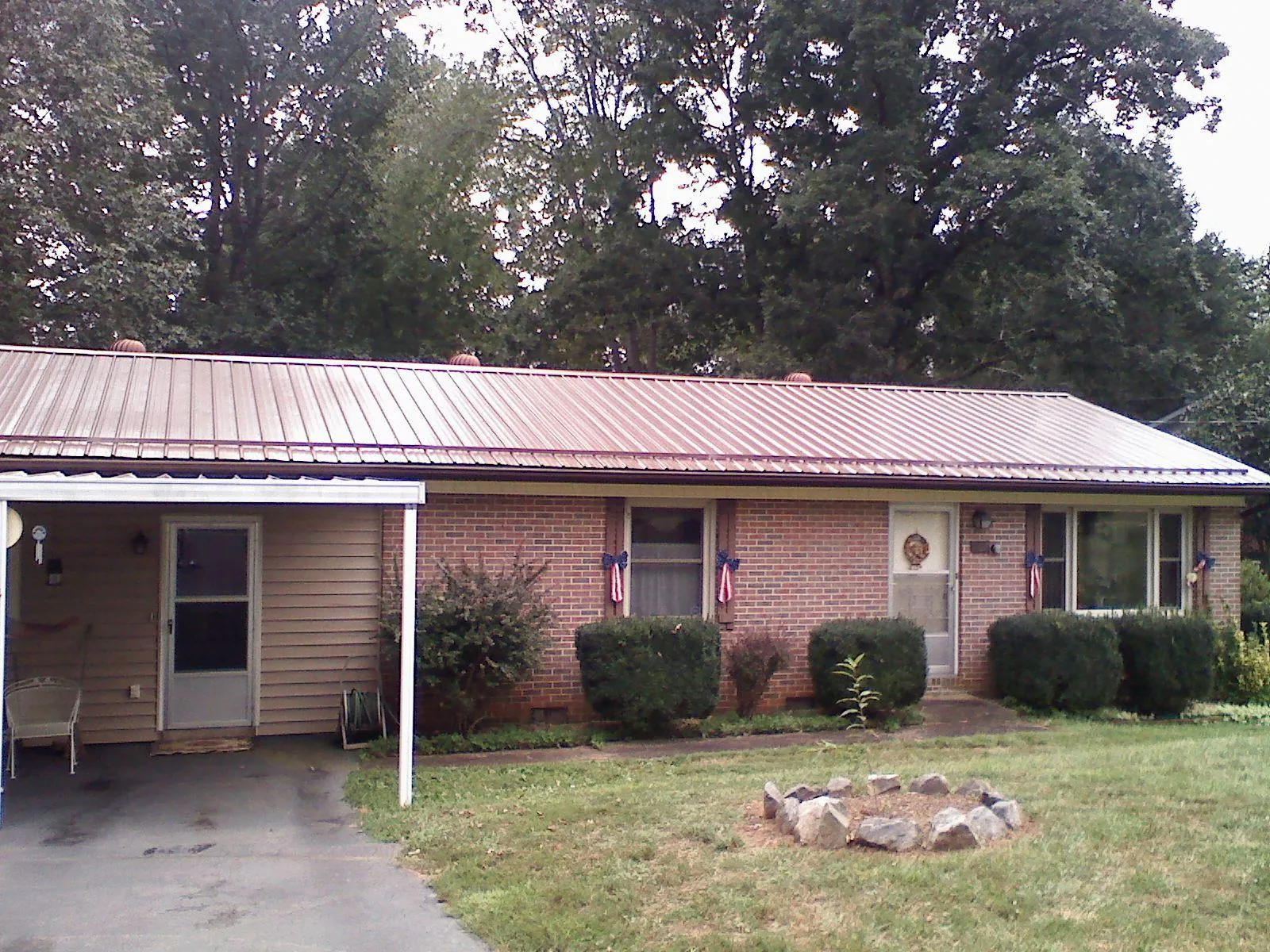Bronze metal roof and carport on a brick ranch home — Roof Repair work by our crew in Jansen